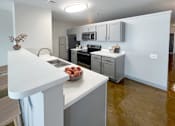 Thumbnail 11 of 19 - A kitchen with white countertops and a bowl of fruit on it.