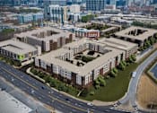 Thumbnail 14 of 14 - A large building complex with a parking lot in front.
