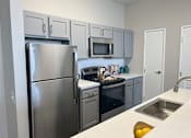 Thumbnail 4 of 19 - A modern kitchen with a stainless steel refrigerator, microwave, and oven.