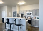 Thumbnail 2 of 19 - A kitchen with white cabinets and black bar stools.