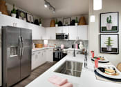 Thumbnail 18 of 22 - A modern kitchen with a stainless steel refrigerator and a dining table set for two.