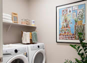 Thumbnail 19 of 22 - A laundry room with two washing machines and a framed picture on the wall.