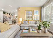 Thumbnail 1 of 11 - A living room with a grey sofa, a coffee table, and a yellow pillow.