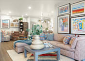 Thumbnail 6 of 11 - A living room with a couch, coffee table, and pictures on the wall.