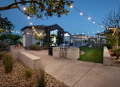 Thumbnail 9 of 22 - A modern house with a glass entrance and outdoor string lights.