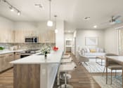 Thumbnail 4 of 14 - A modern kitchen with a white island and wooden cabinets.