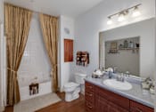 Thumbnail 17 of 29 - A bathroom with a white toilet, a sink, and a bathtub with brown curtains.