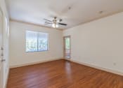 Thumbnail 18 of 24 - A room with a ceiling fan and wooden flooring.