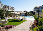 Thumbnail 1 of 14 - A poolside area with chairs and umbrellas.