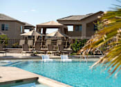 Thumbnail 34 of 34 - A pool area with a few chairs and umbrellas.