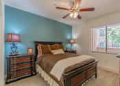 Thumbnail 13 of 24 - A bedroom with a bed, dresser, and ceiling fan.