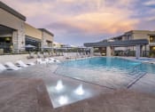 Thumbnail 31 of 39 - a swimming pool with chaise lounge chairs and umbrellas in front of a hotel