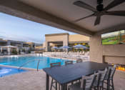 Thumbnail 33 of 39 - a patio with a table and chairs and a pool in the background