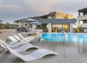 Thumbnail 35 of 39 - a pool with white lounge chairs and umbrellas