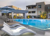 Thumbnail 36 of 39 - a swimming pool with lounge chairs and umbrellas in front of a building