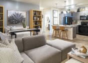 Thumbnail 8 of 39 - a living room and kitchen area with a gray couch and a black dining table