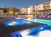 Thumbnail 3 of 51 - a swimming pool at night at an apartment complex with a hot tub