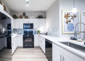 Thumbnail 7 of 51 - a large kitchen with white cabinets and black appliances