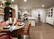Thumbnail 11 of 14 - A dining room with a table set for two and a kitchen in the background.
