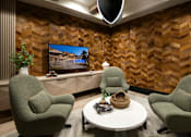 Thumbnail 7 of 34 - A modern living room with a large screen TV and two green armchairs.