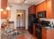 Thumbnail 39 of 51 - a kitchen with wood cabinets and black appliances