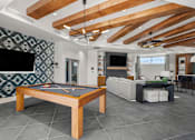 Thumbnail 26 of 56 - A pool table is in the middle of a room with a television and a couch.