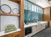 Thumbnail 33 of 56 - A kitchen with a white counter top and a green tile backsplash.