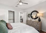 Thumbnail 47 of 56 - A bedroom with a bed, dresser, mirror, and a ceiling fan.