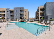 Thumbnail 41 of 56 - A swimming pool surrounded by lounge chairs and buildings.