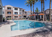 Thumbnail 4 of 29 - A swimming pool surrounded by palm trees and apartment buildings.