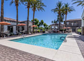 Thumbnail 3 of 29 - A swimming pool surrounded by palm trees and patio furniture.