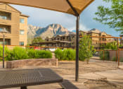 Thumbnail 27 of 29 - a picnic table in a courtyard with buildings and mountains in the background