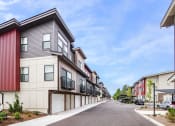 Thumbnail 23 of 30 - a street of townhomes with cars parked on the side of the road