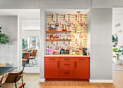Thumbnail 13 of 34 - a kitchen with an orange counter and a wall covered in books