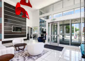 Thumbnail 16 of 22 - a lobby with a white couch and chair and a glass door