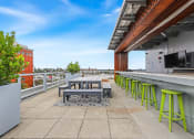 Thumbnail 16 of 27 - a rooftop patio with tables and stools and a television