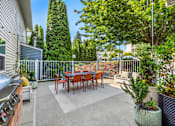 Thumbnail 14 of 34 - A patio with a table and chairs surrounded by a fence and trees.