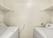 Thumbnail 16 of 26 - Two white washing machines in a laundry room.