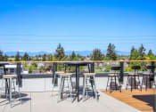 Thumbnail 41 of 53 - a rooftop bar with bar stools and tables with mountains in the background