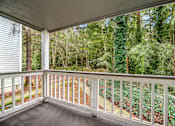 Thumbnail 26 of 26 - A white railing on a porch leads to a wooded area.