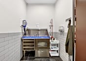 Thumbnail 30 of 32 - A clean, white-tiled kitchen with a stainless steel sink and a blue mat on the counter.
