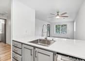 Thumbnail 15 of 43 - A modern kitchen with a white countertop and a stainless steel sink.