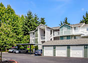 Thumbnail 4 of 34 - A row of townhouses with garages and cars parked in front.