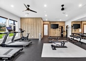 Thumbnail 6 of 32 - A spacious home gym with treadmills, exercise bikes, and a television.