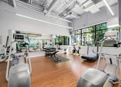 Thumbnail 24 of 38 - a gym with exercise equipment and windows in a room with wood floors