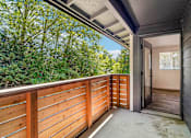 Thumbnail 21 of 43 - A balcony with a wooden railing and a view of trees.