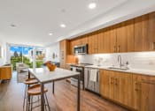 Thumbnail 11 of 53 - a kitchen with wooden cabinets and a table with three stools