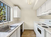 Thumbnail 11 of 26 - A kitchen with white appliances and cabinets.