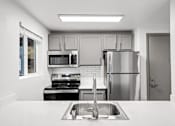 Thumbnail 8 of 13 - A kitchen with a stove, microwave, refrigerator, and sink.
