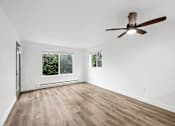 Thumbnail 12 of 13 - A room with a ceiling fan and wooden flooring.